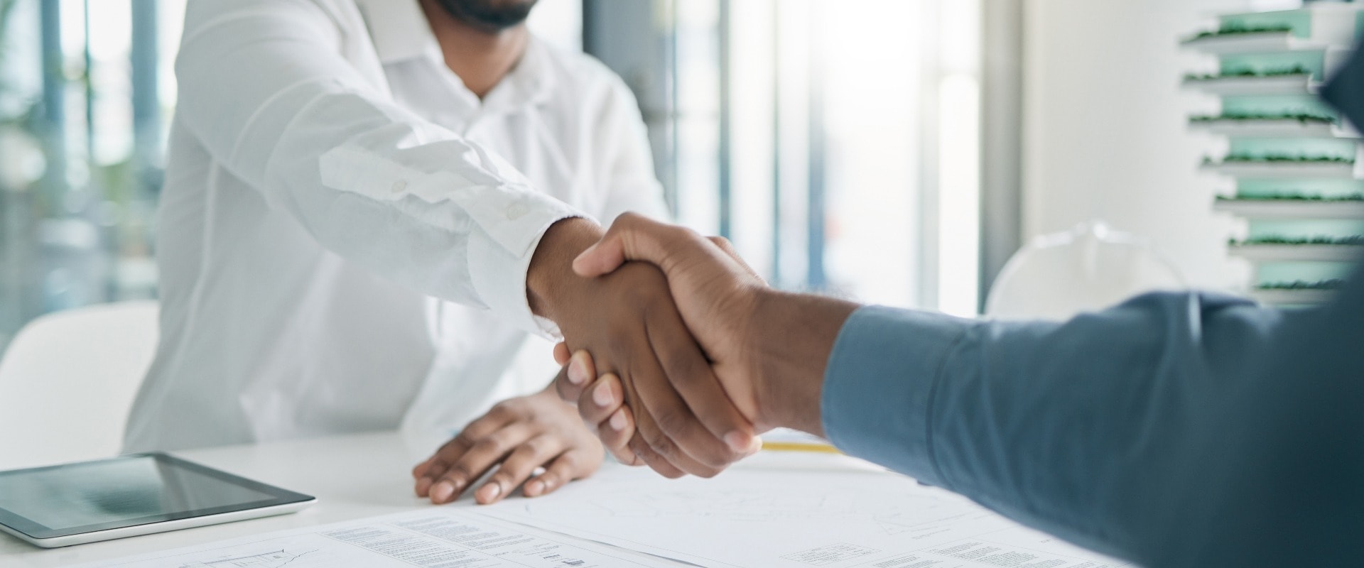 Black man, shaking hands and architecture with architect hiring, interview and onboarding, office and blueprint plan. Human resources, recruitment and partnership with deal, contract and thank you